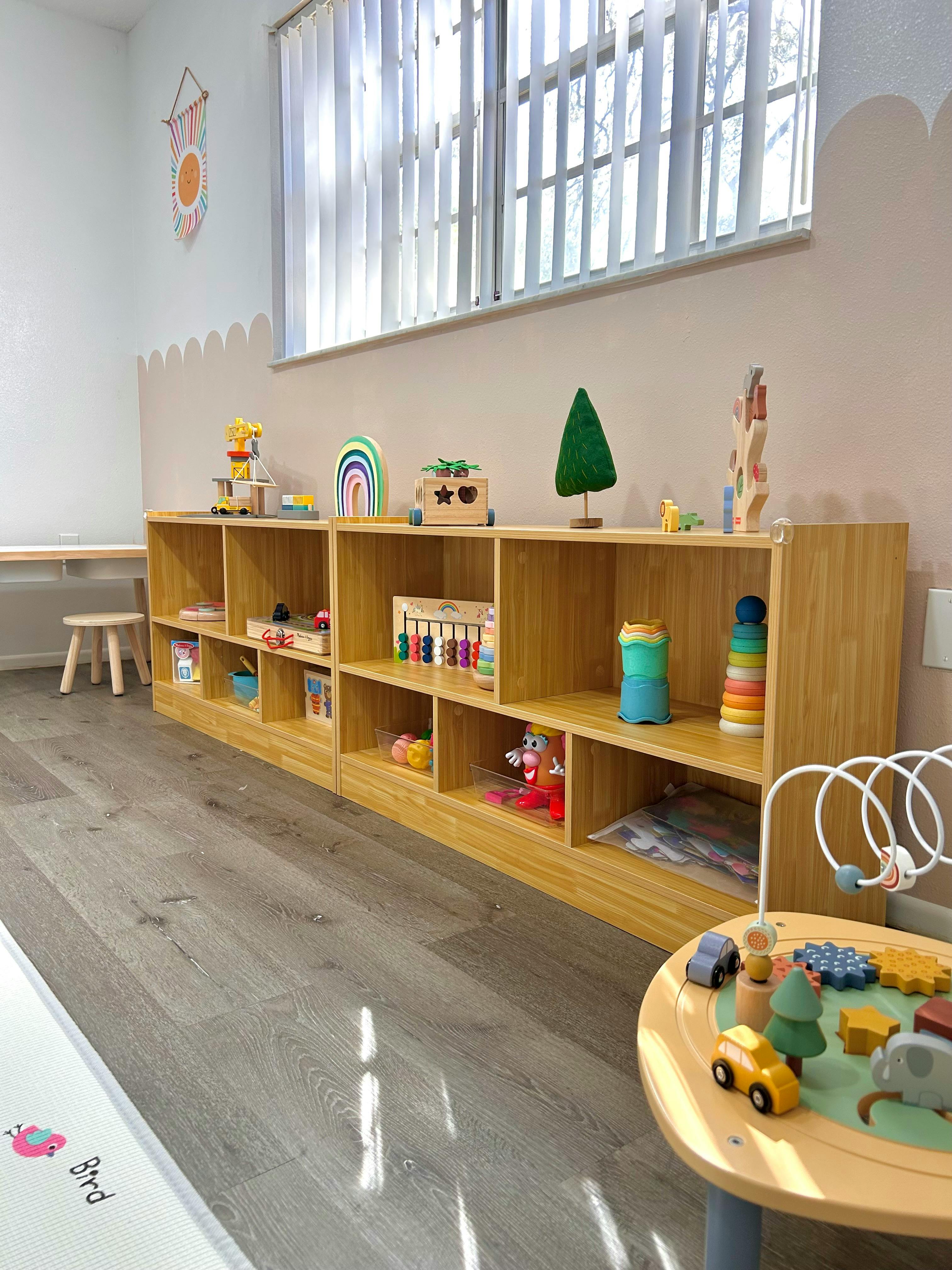 Wooden shelves filled with various toys in a bright room