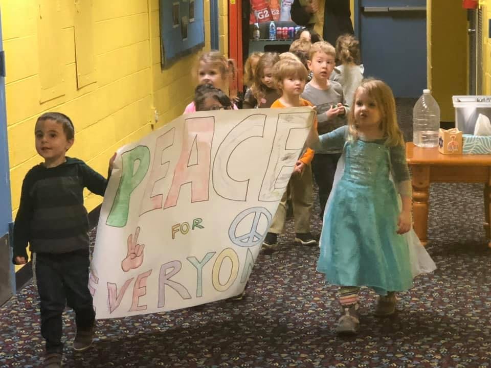 Children holding a banner that says "Peace for Everyone"