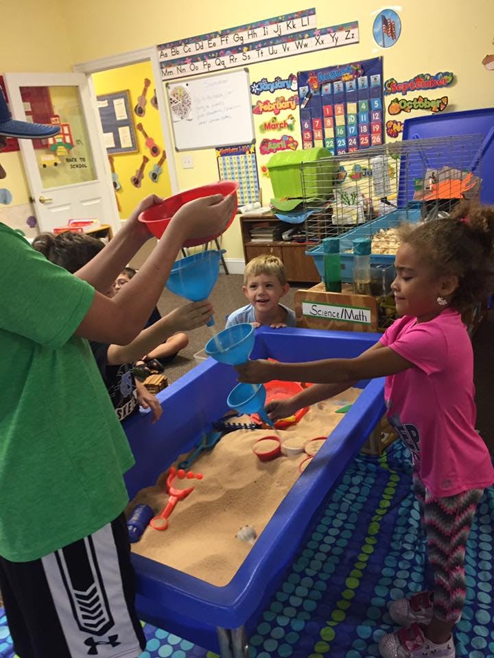 Children playing with sand and funnels in a classroom