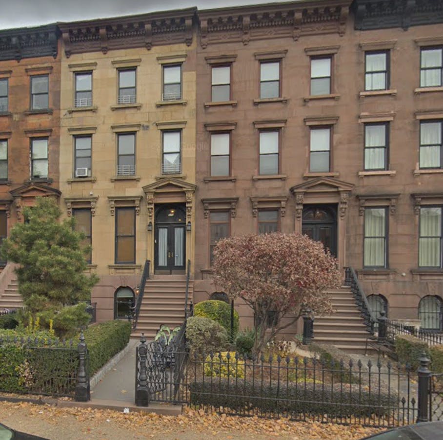 Row of brownstone buildings with front stoops and trees