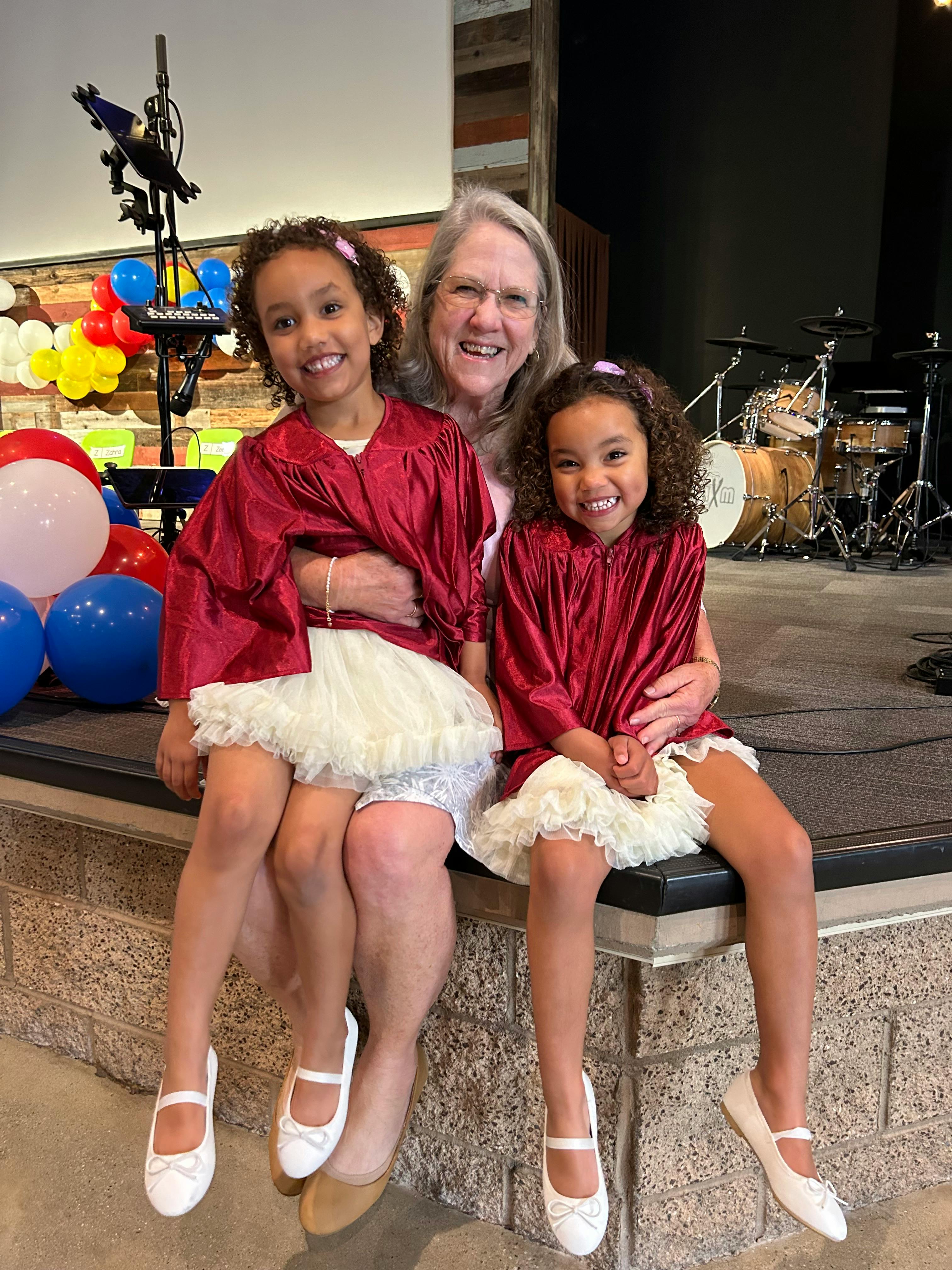 Person with two children in red robes and white skirts
