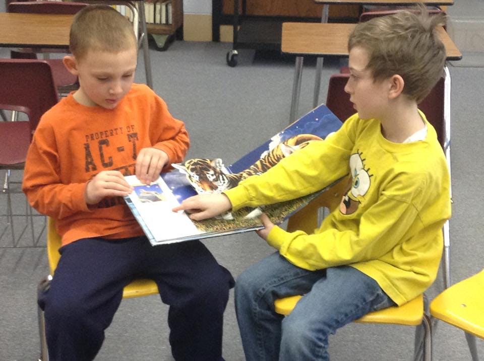 Two children sitting and looking at a book together