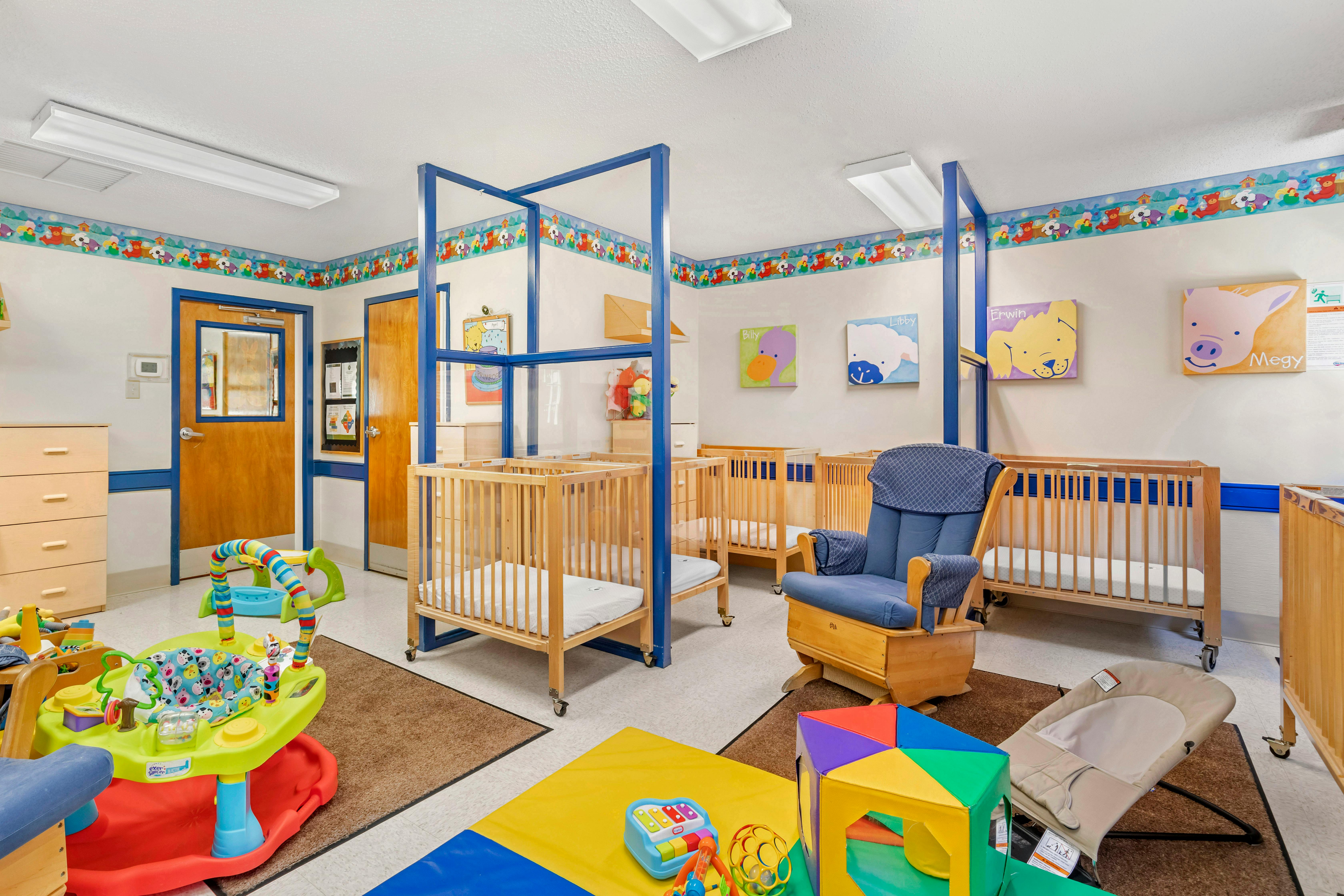 A colorful nursery room with multiple cribs, a rocking chair, and various baby toys