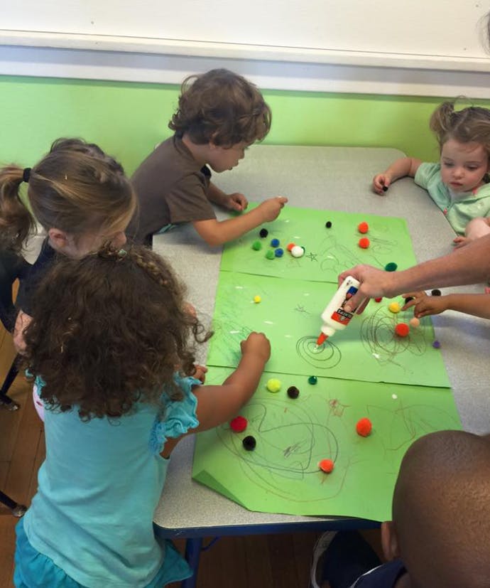 Children doing an art project with pom-poms and glue