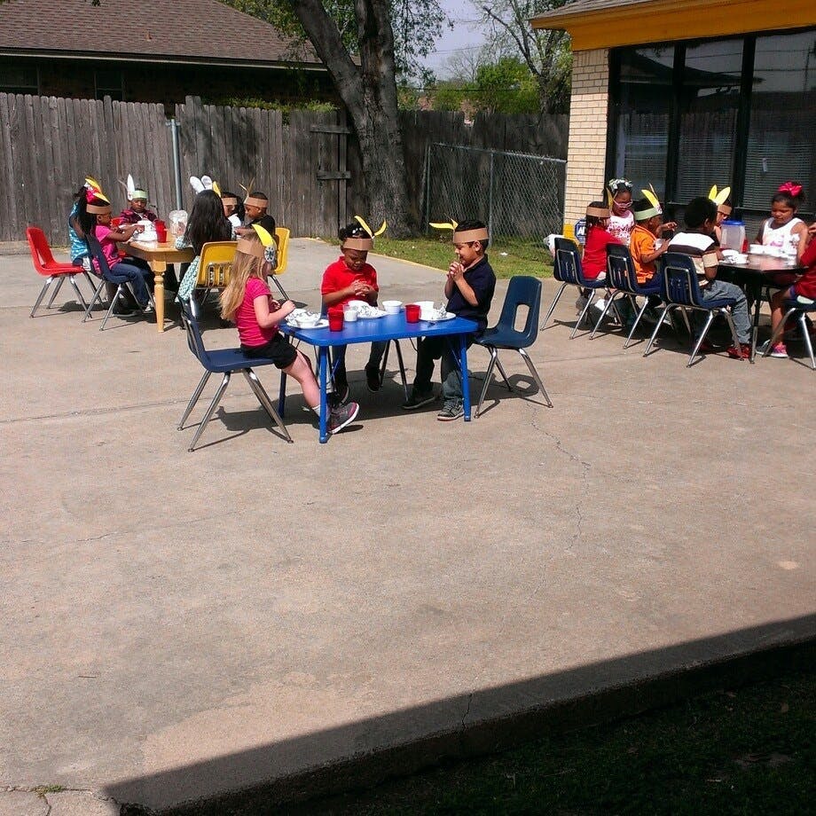 Children sitting at tables outdoors