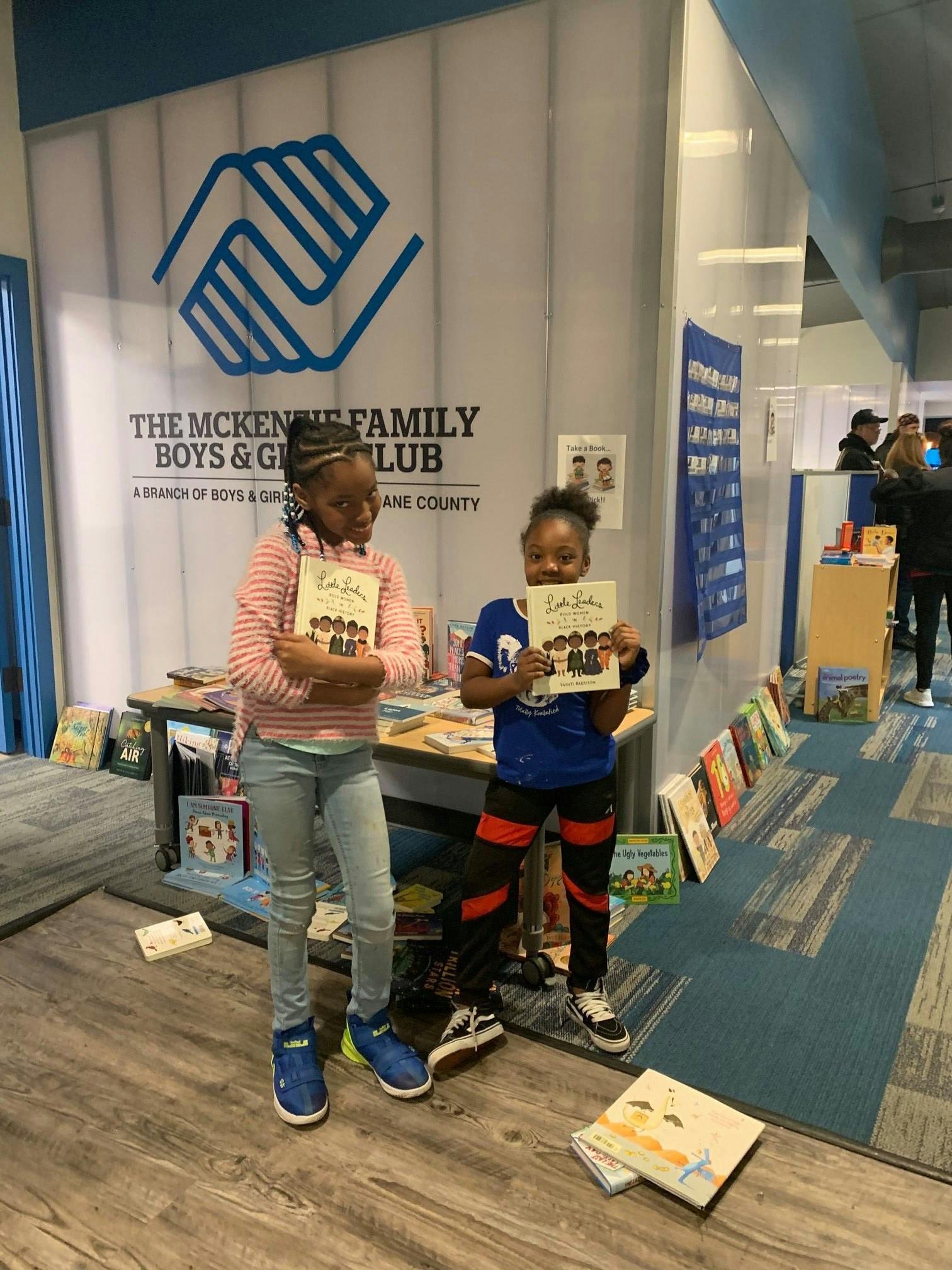 Two children holding books in front of a Boys & Girls Club sign