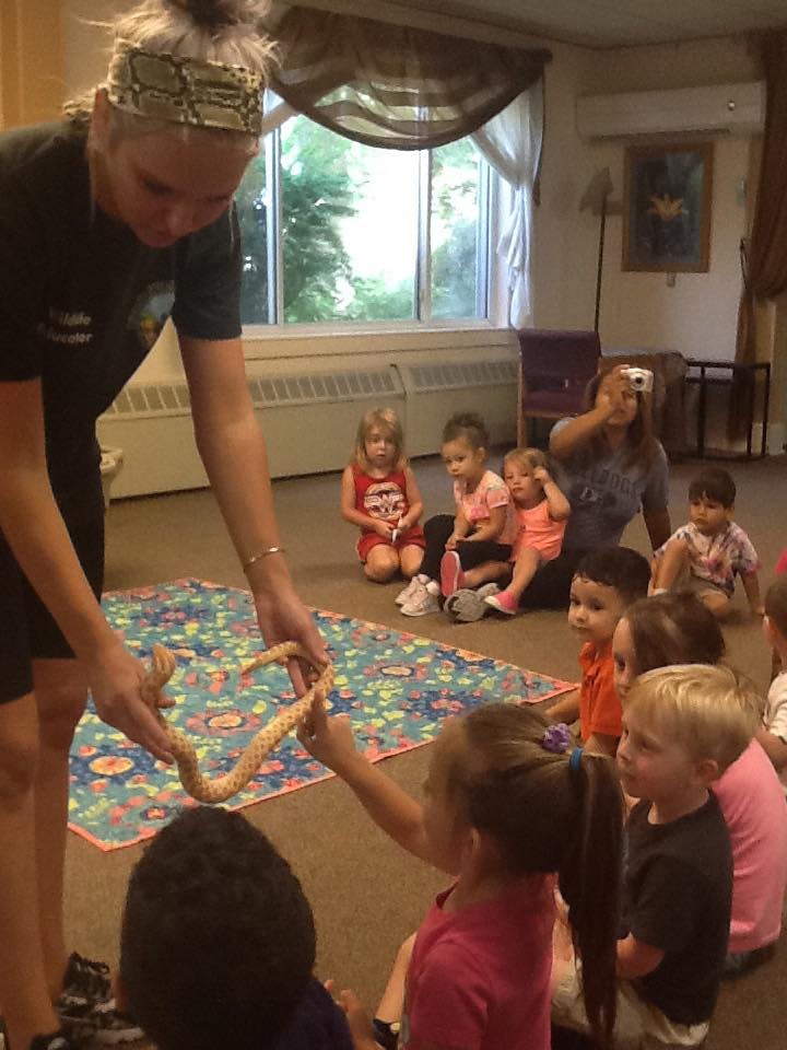 Person holding a snake for children to see in a room