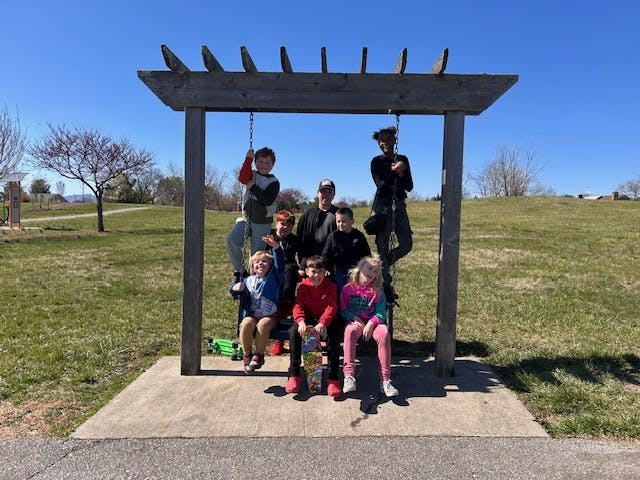 Group of people and children posing under a wooden structure