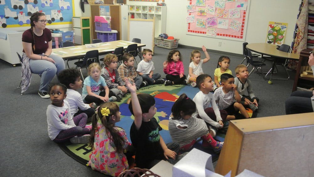 Adult and children sitting on floor in classroom
