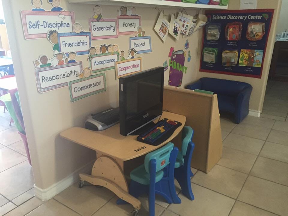 Computer on a small desk with two chairs in a classroom