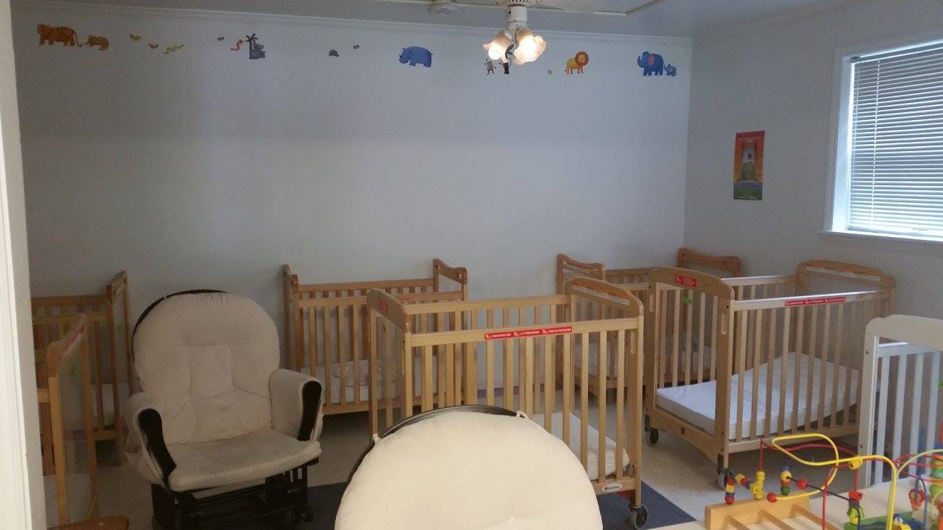 Room with multiple wooden cribs and a glider chair
