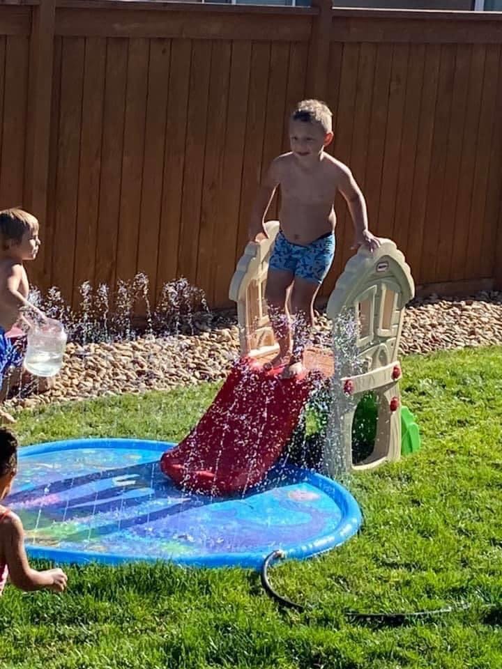 Child on a red water slide in a splash pad
