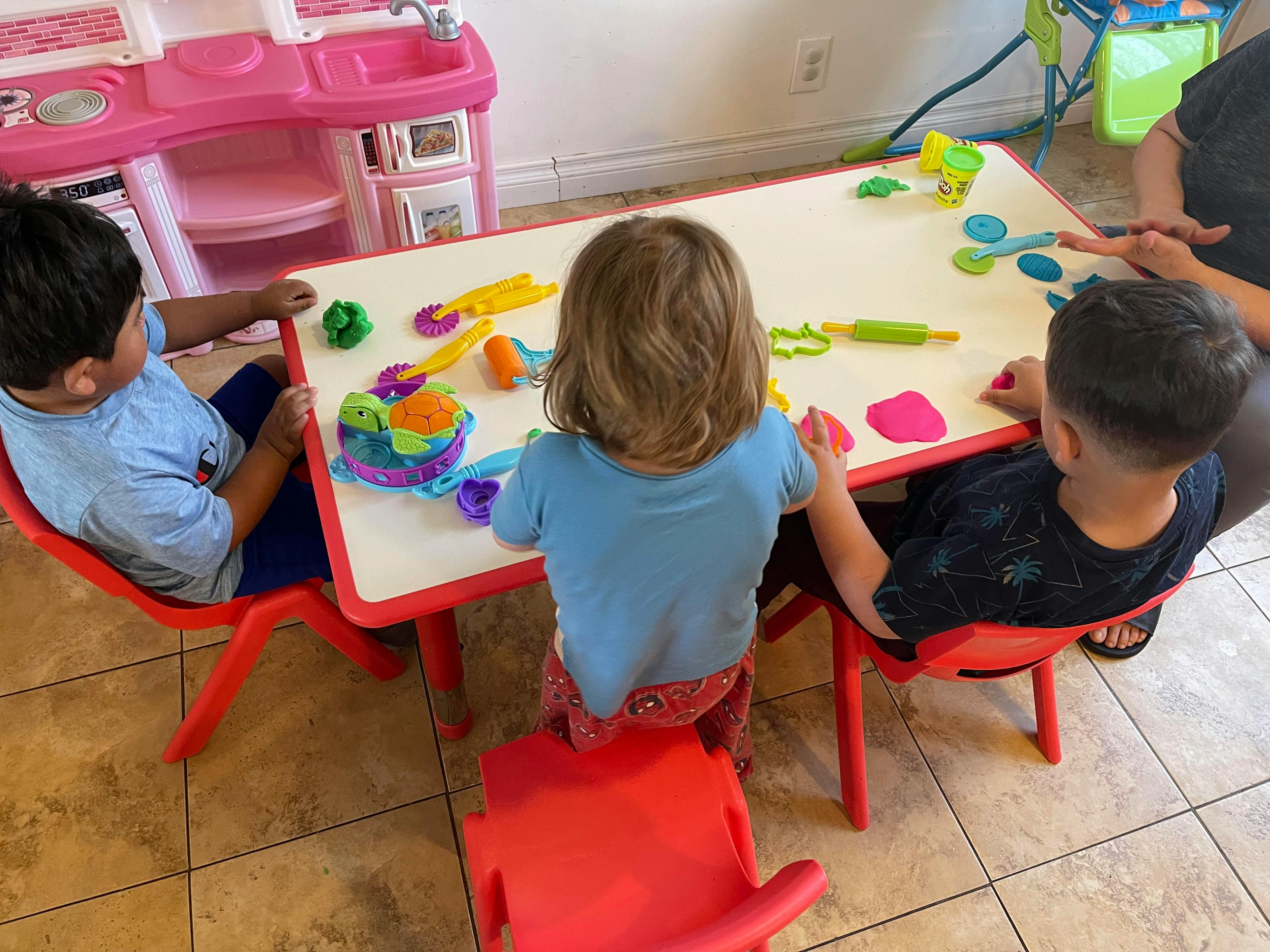 Three children playing with modeling clay at a table