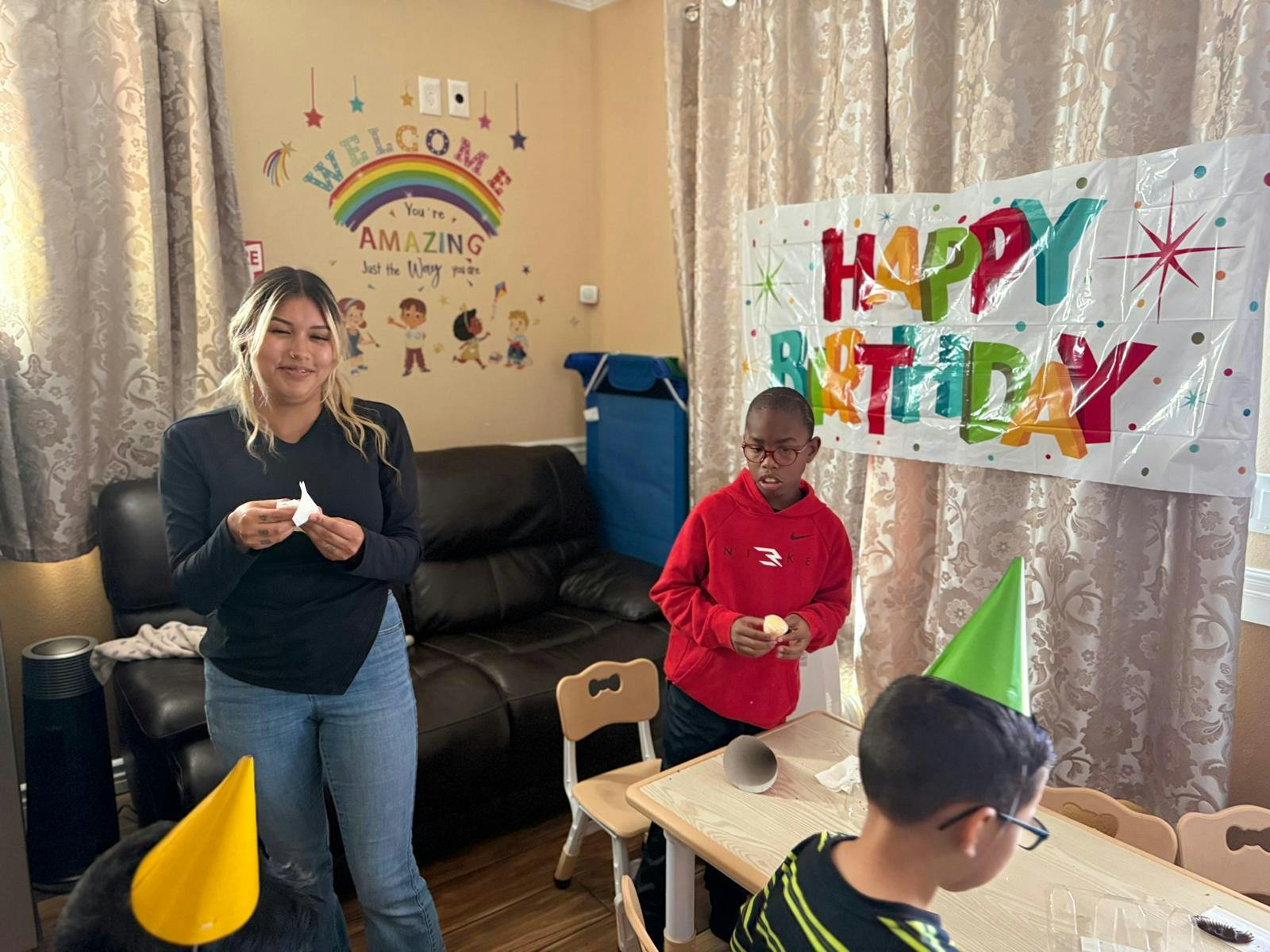 A person and children at a birthday celebration with banners and party hats