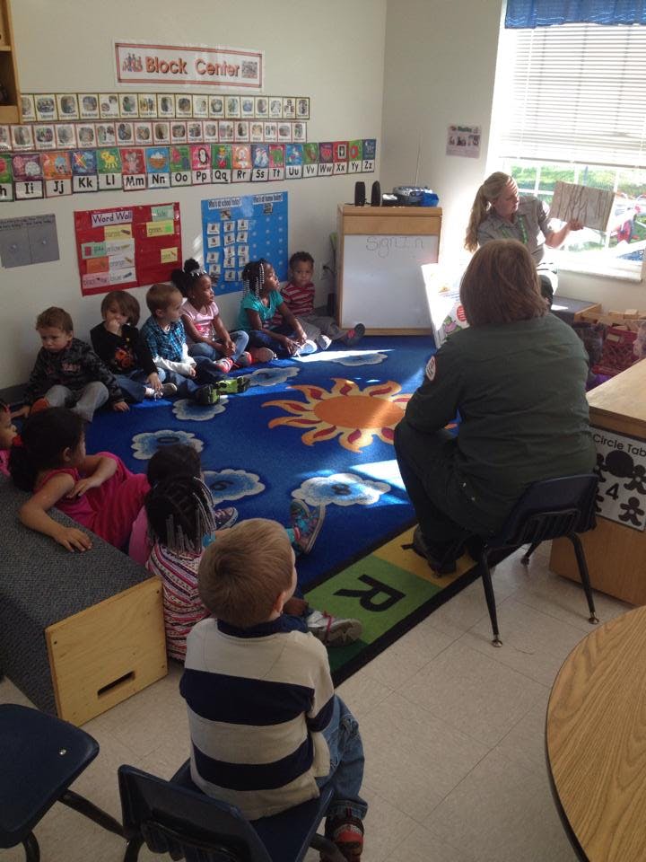 Adult reading to children sitting on a rug in a classroom