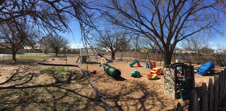 Outdoor playground with various play structures and bare trees