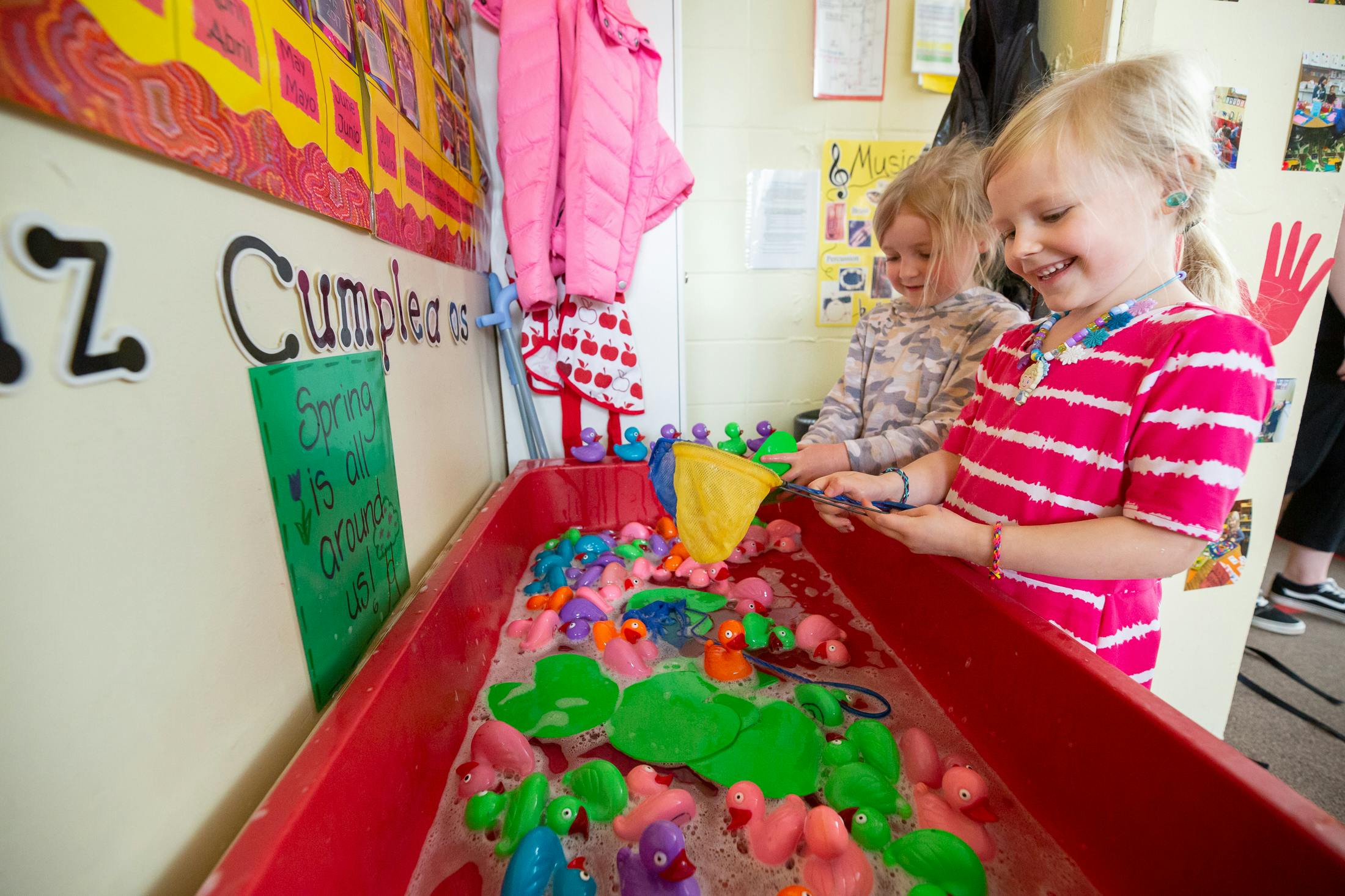 Two children playing with floating toys in a red bin