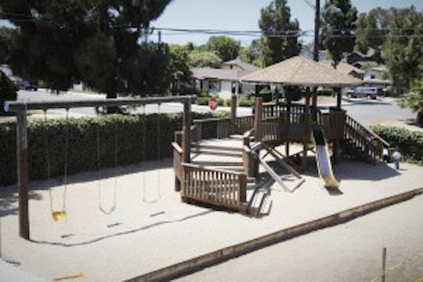 Wooden playground structure with swings and a slide