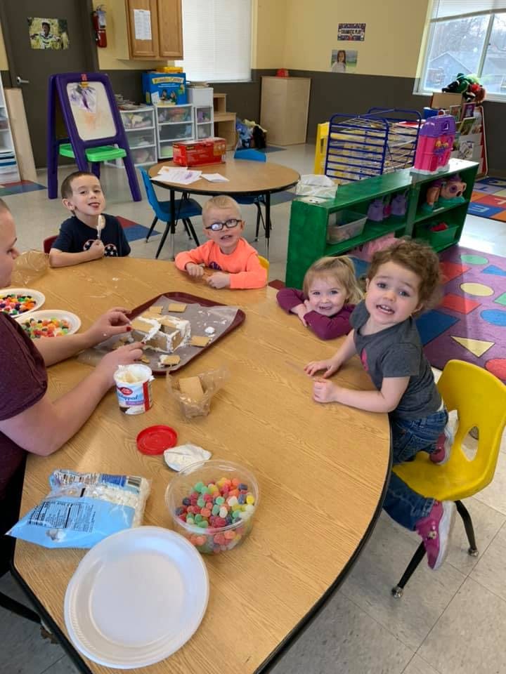 Adult and children at a table with craft supplies