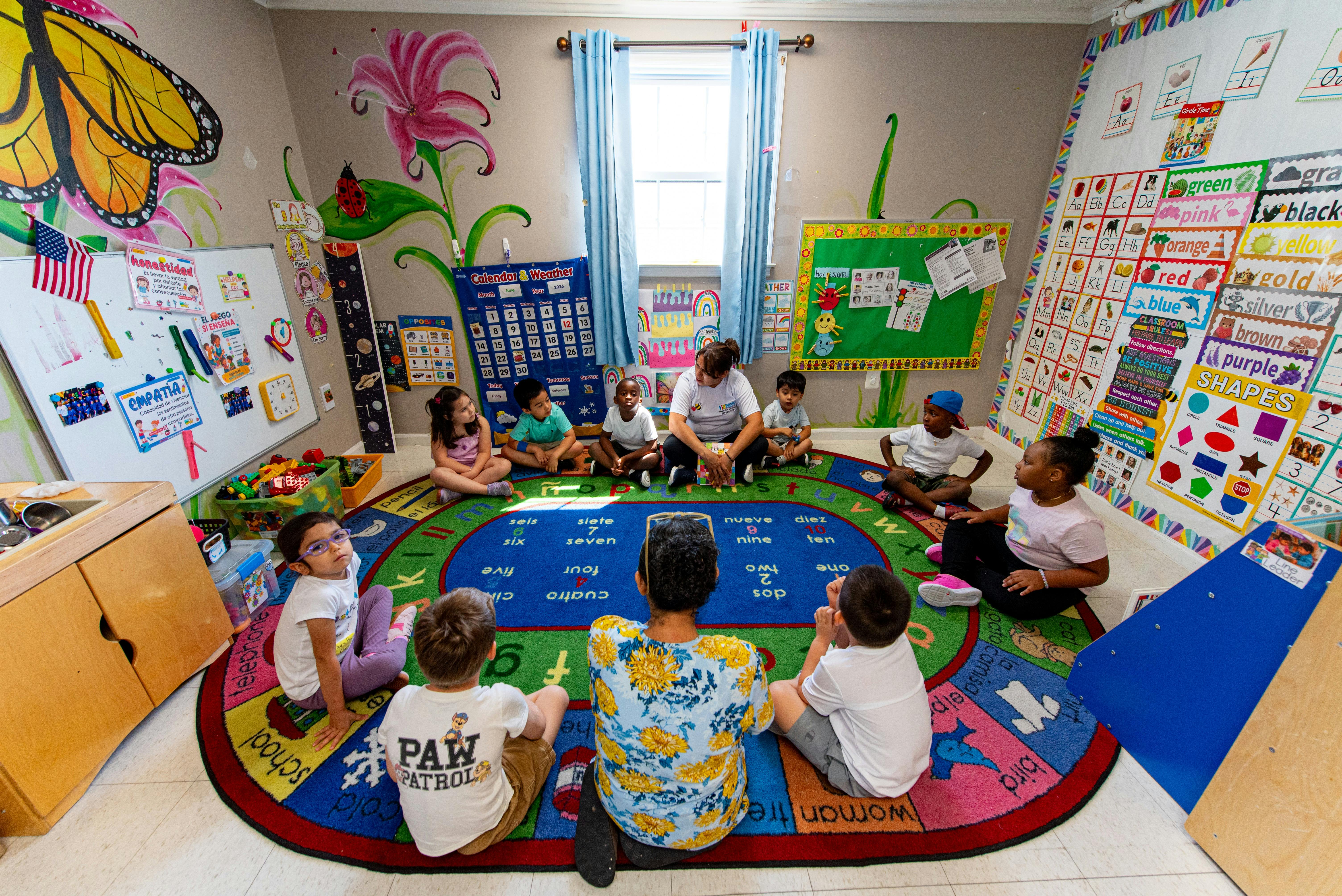 Teacher and children sitting in a circle on a rug in a classroom