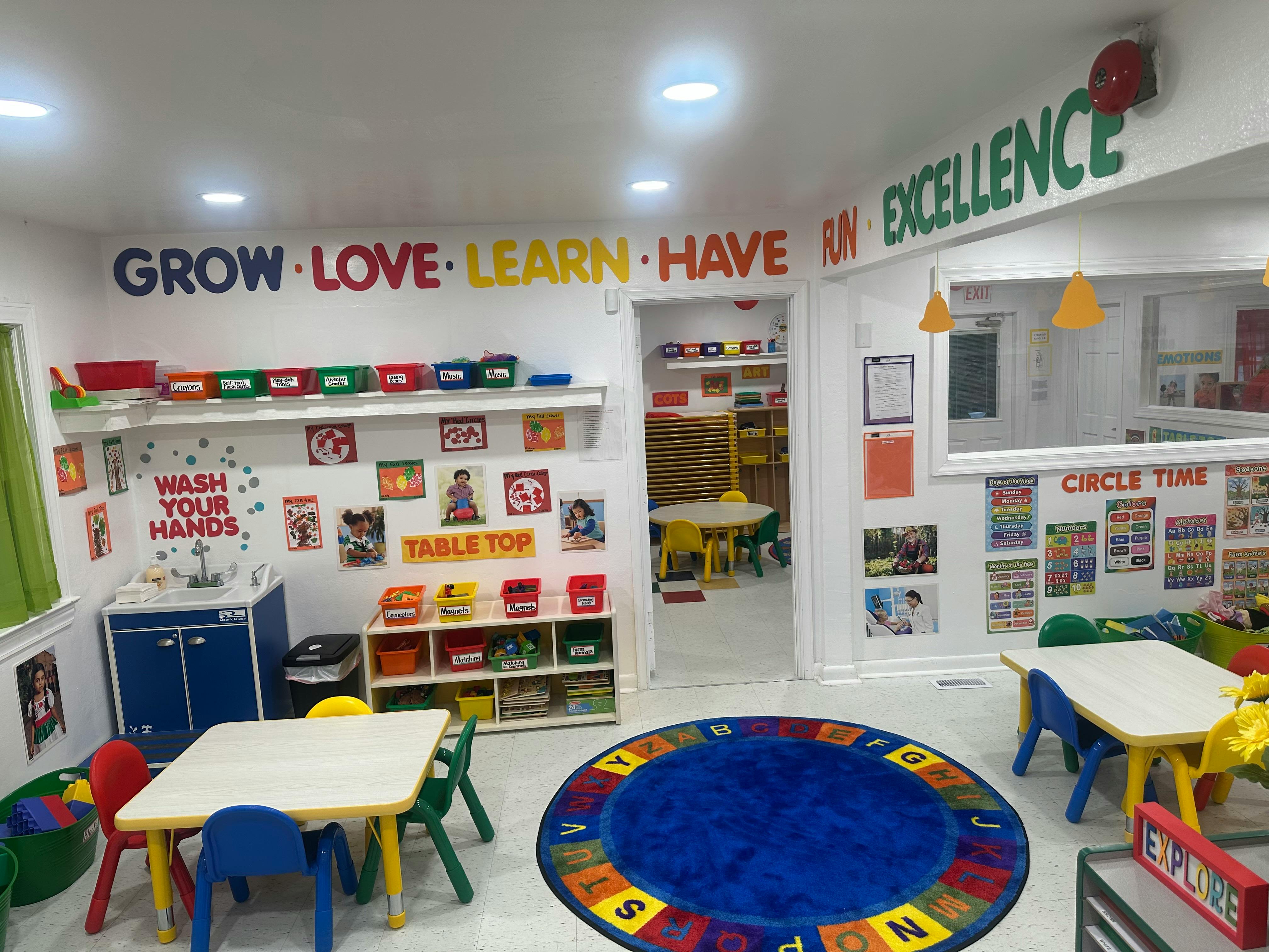 Preschool classroom with small tables and chairs, a round rug, and wall decorations