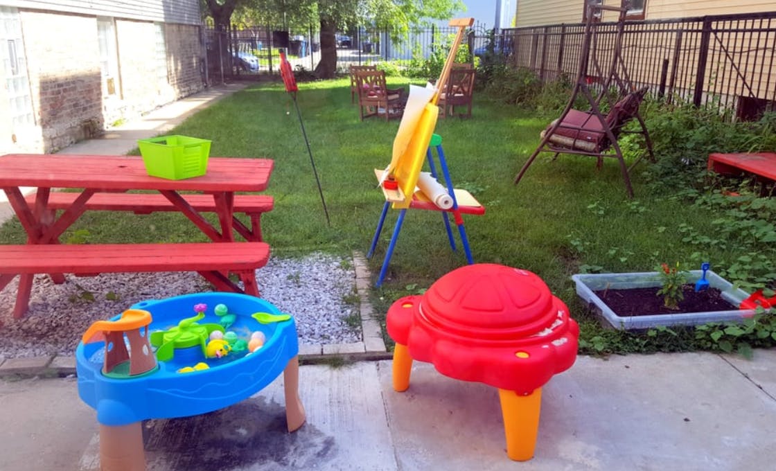 Outdoor play area with red picnic table, blue water table, and easel