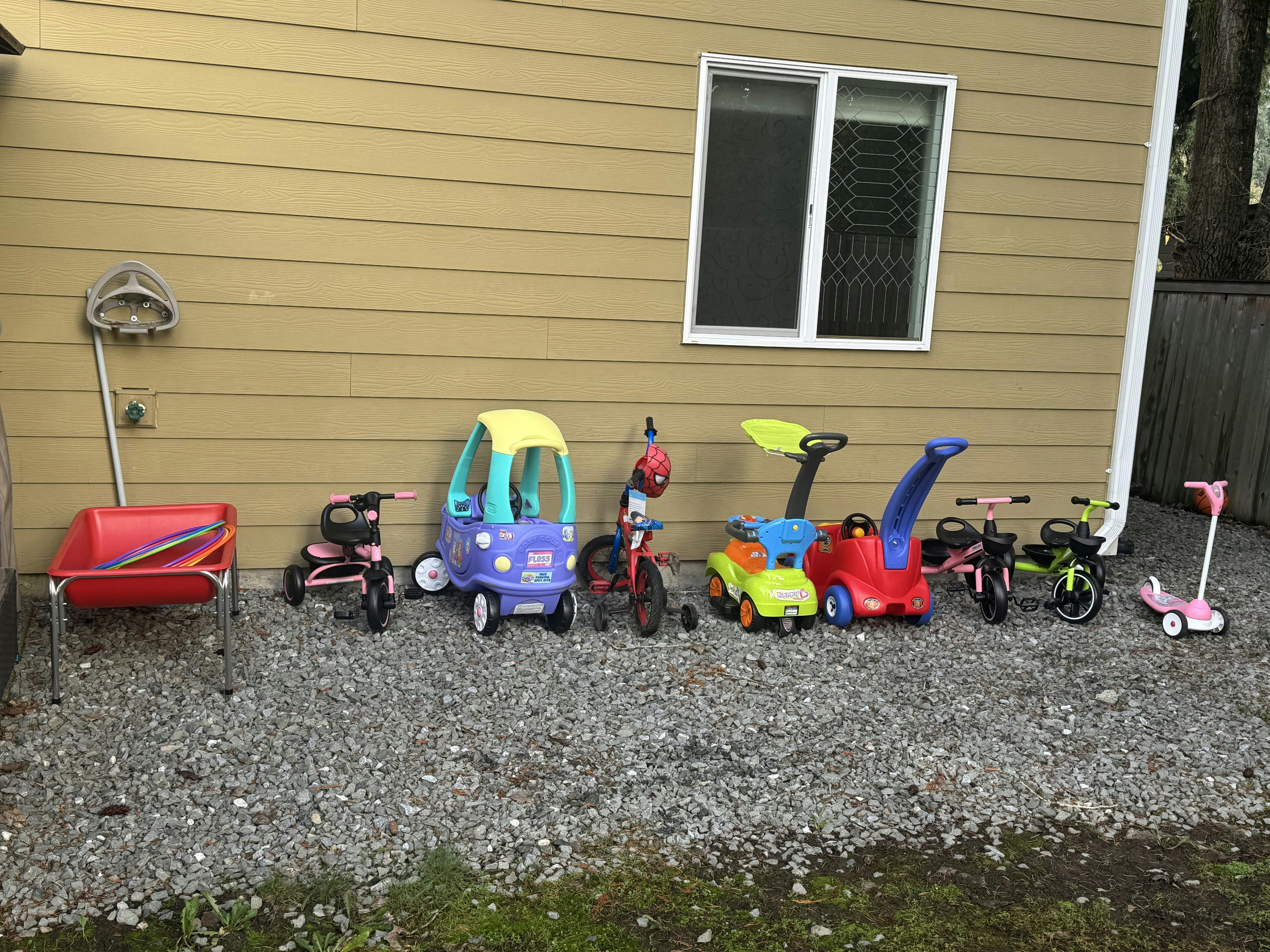 Variety of children's ride-on toys, tricycles, and scooters lined up