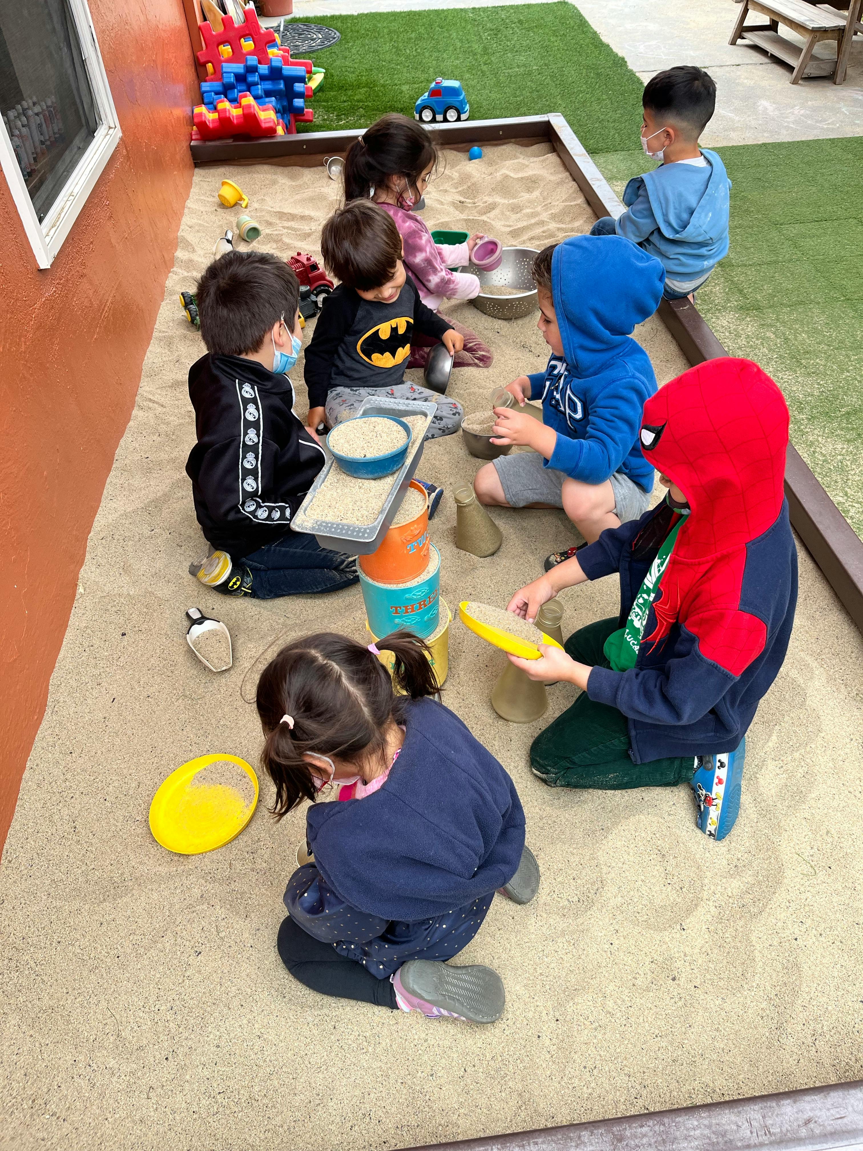 Children playing in a sandbox with toys