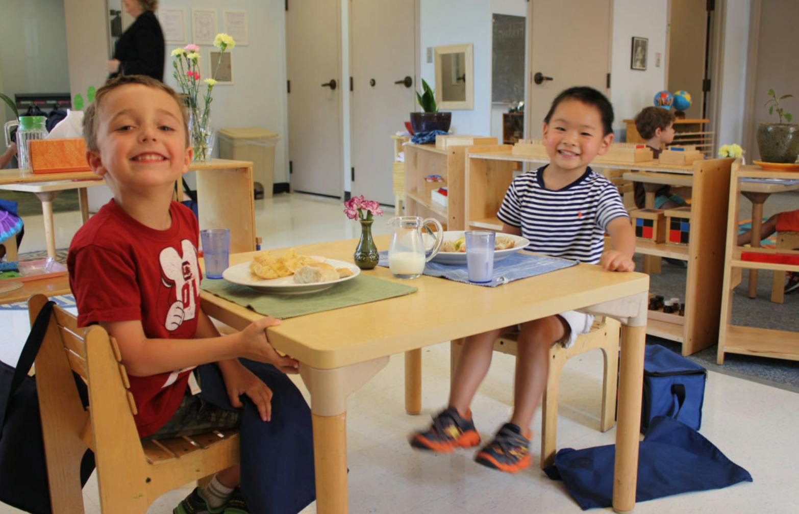 Two children sitting at a table with plates and drinks