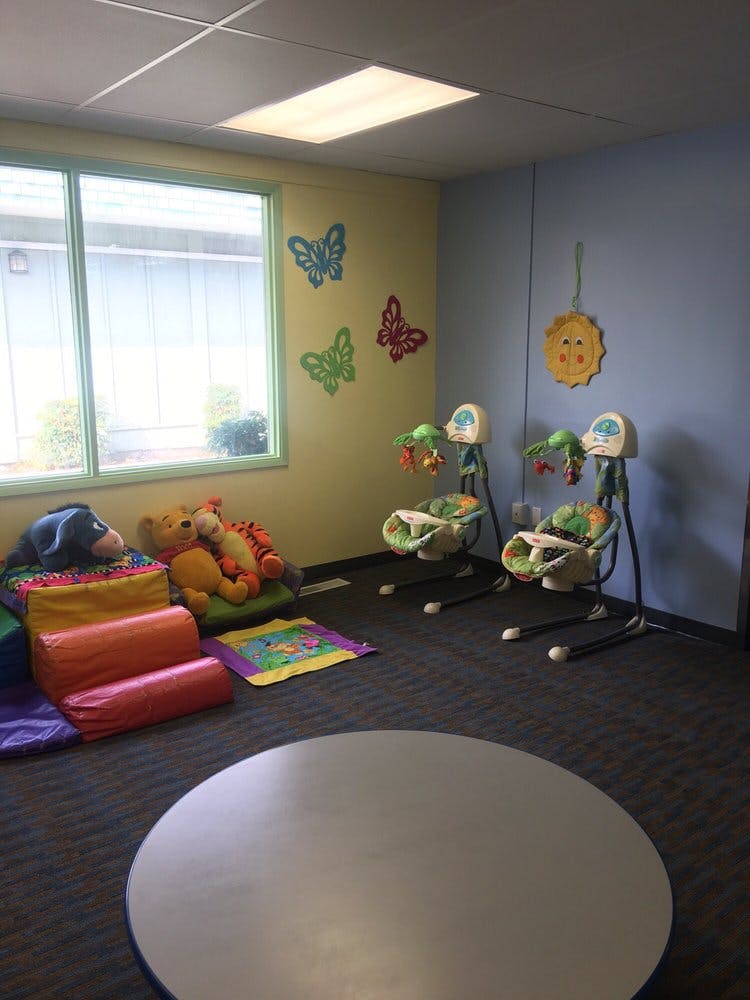 Childcare room with two baby swings, stuffed animals, and soft play blocks