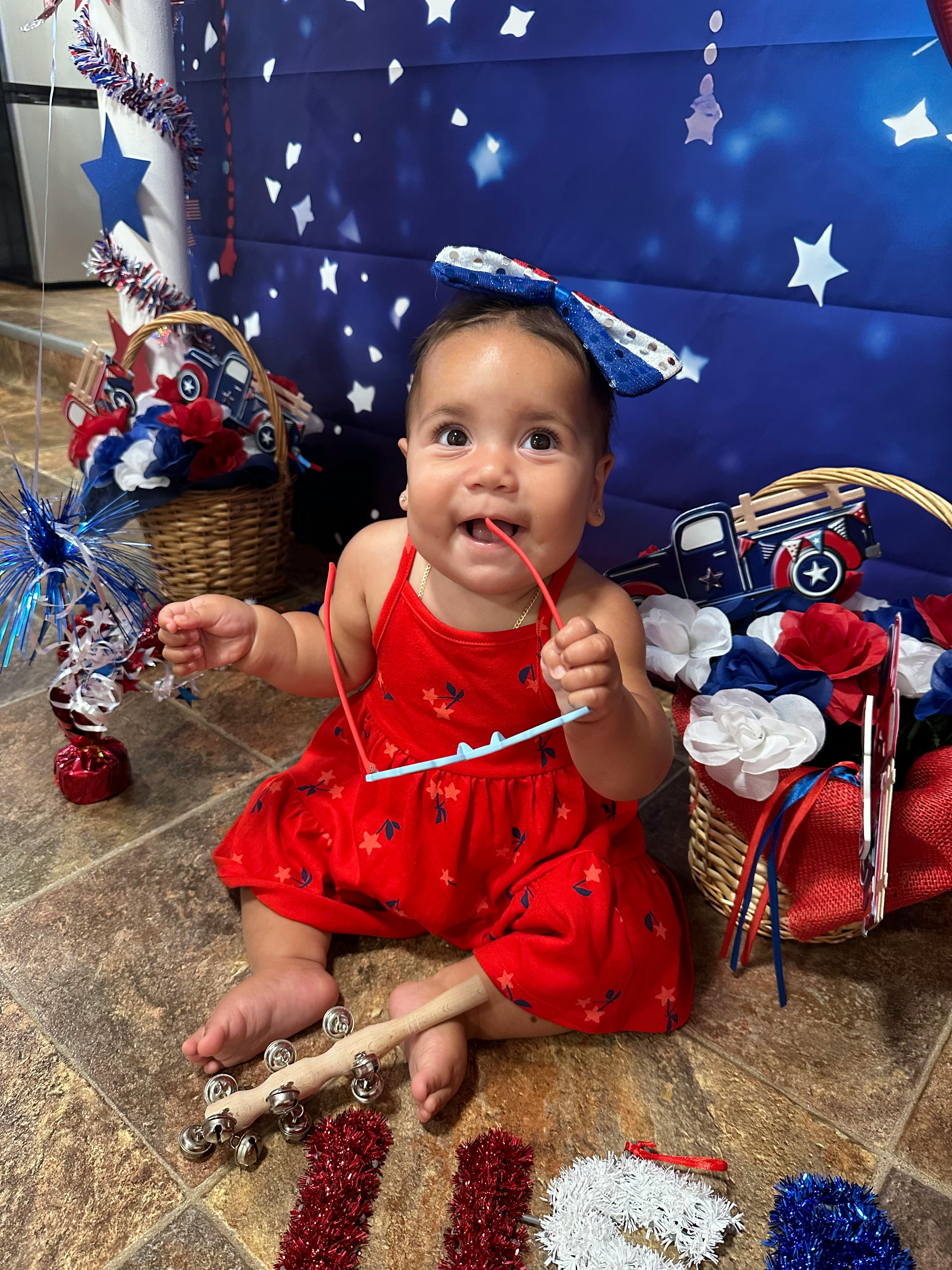 Child in red dress holding red glasses in mouth