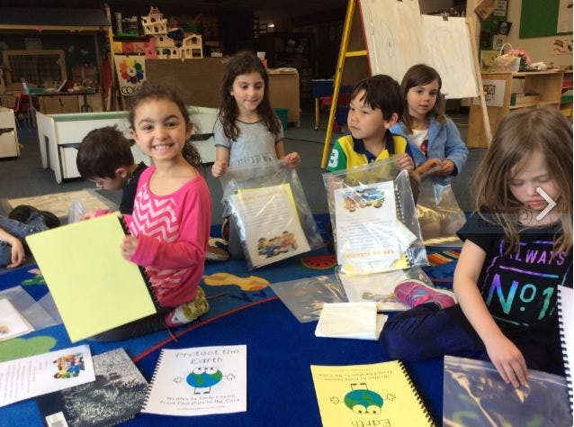 Children sitting on a rug with papers and books