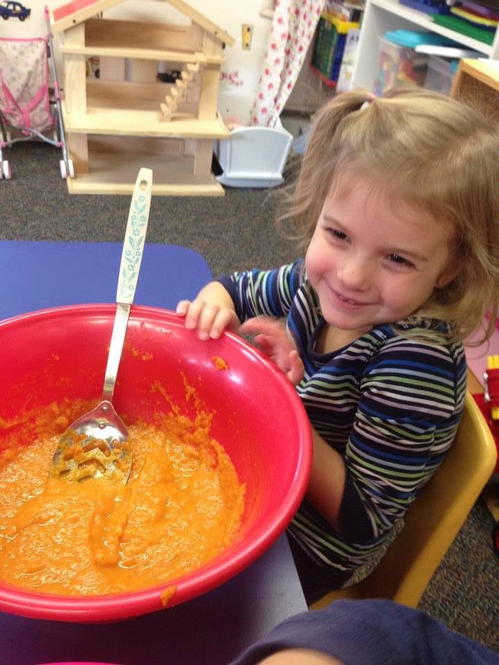 Child with a large red bowl of orange mixture and a spoon