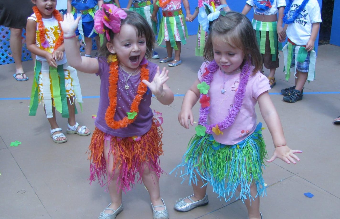 Two children in hula skirts and leis dancing