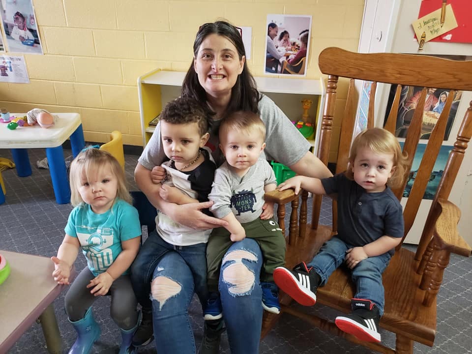 Person sitting with four children in a classroom