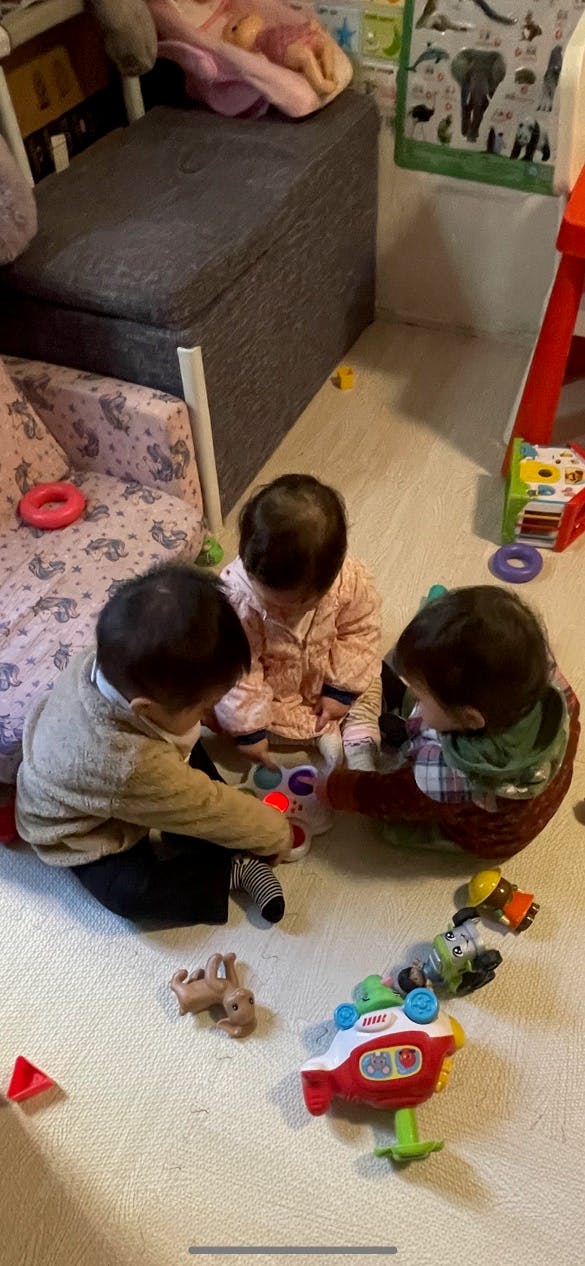 Three children sitting on the floor playing with toys