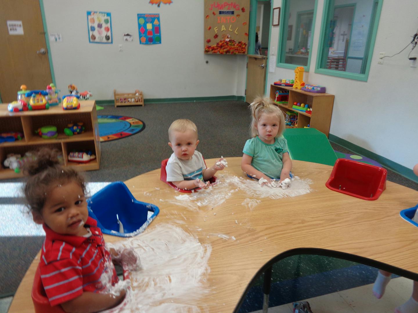 Three children playing with white powder at a table