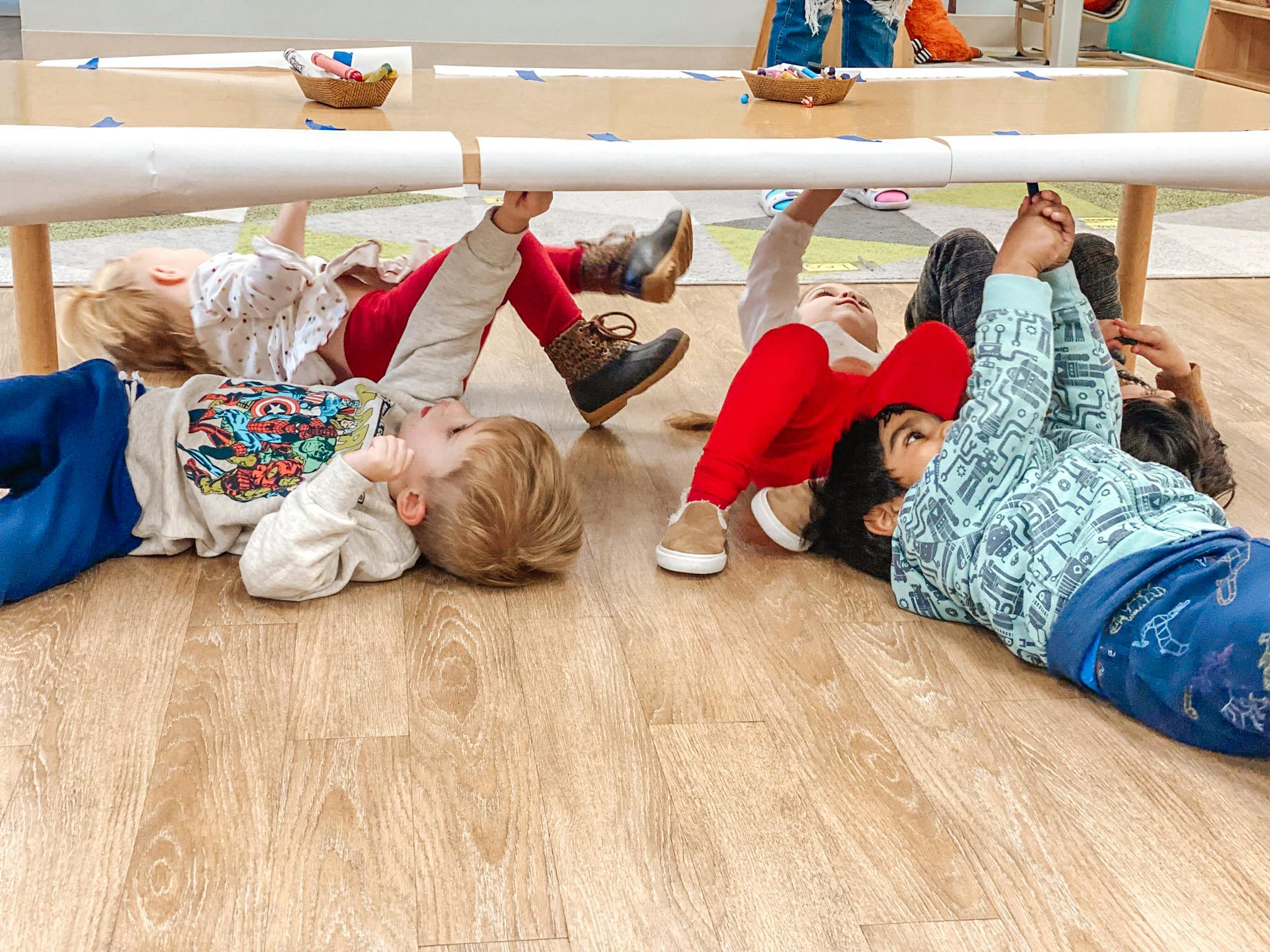 Children lying on the floor under a table