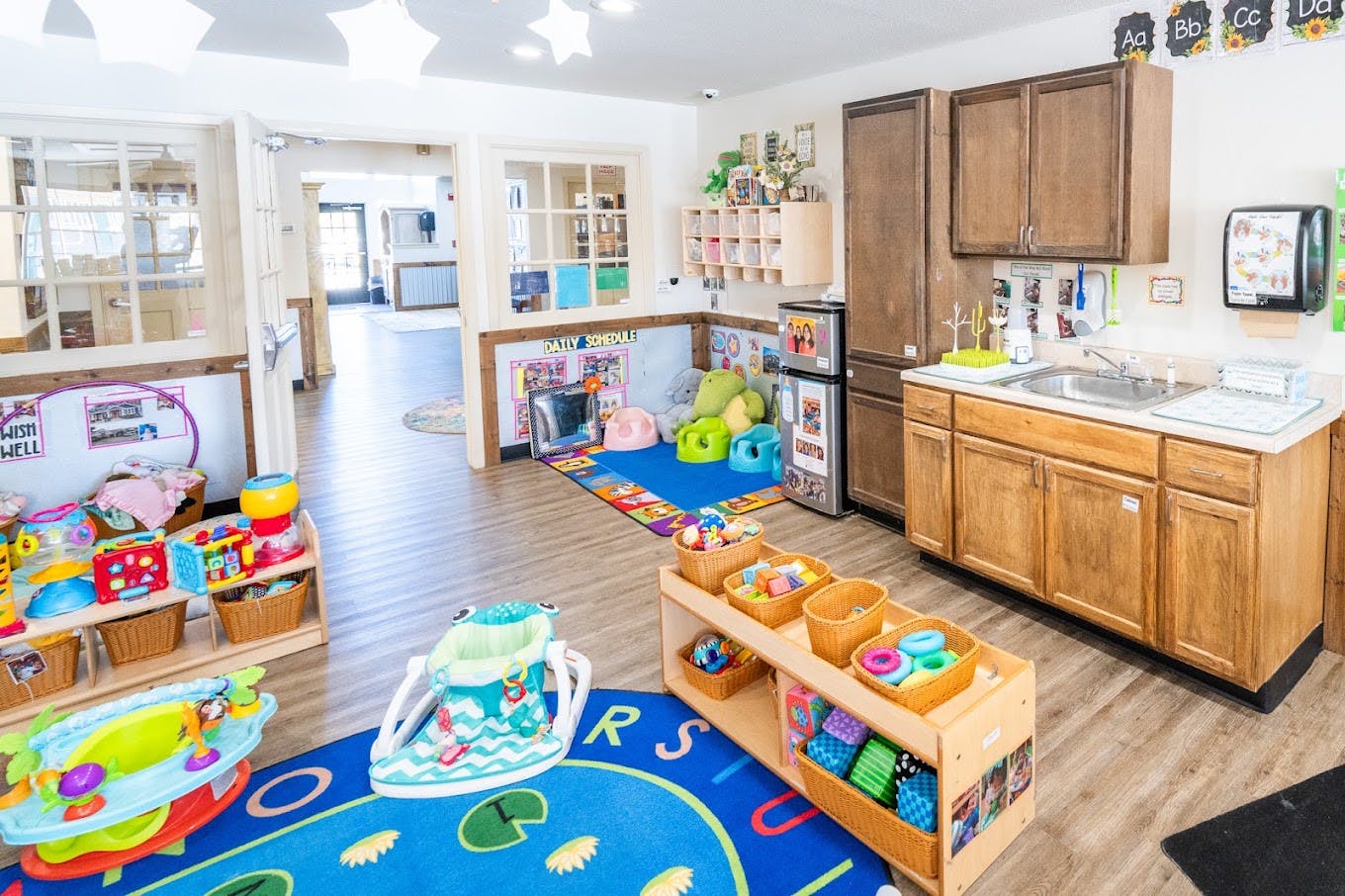 Childcare classroom with toys, play mats, and a kitchen sink area