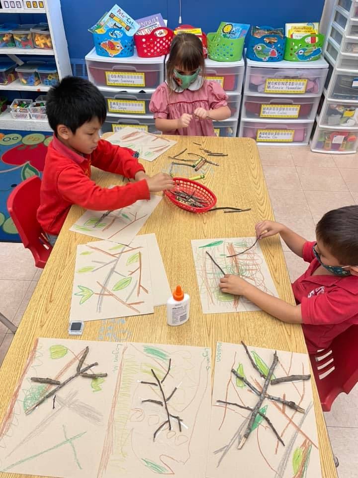 Children making art with sticks and glue in a classroom