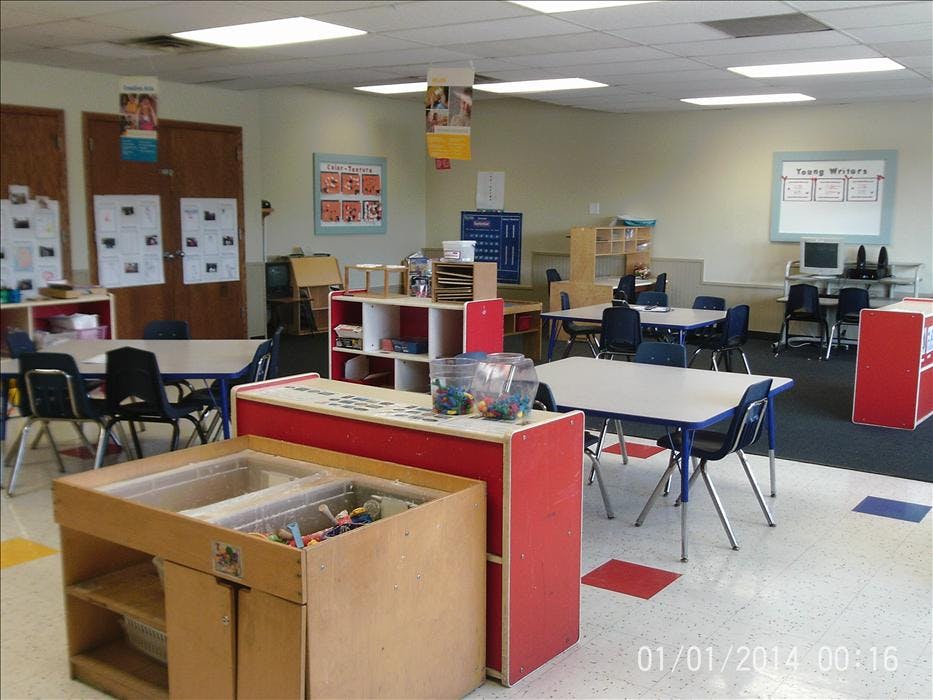 An empty classroom with small tables, chairs, and learning materials