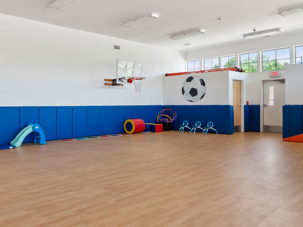 Indoor play area with a small slide, basketball hoop, and soccer ball painted on the wall
