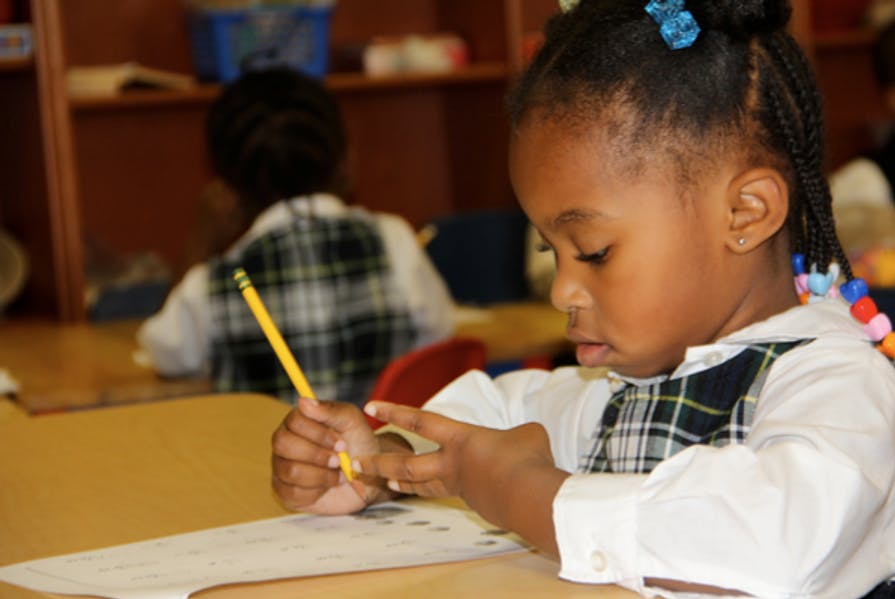 Child in a classroom writing with a pencil