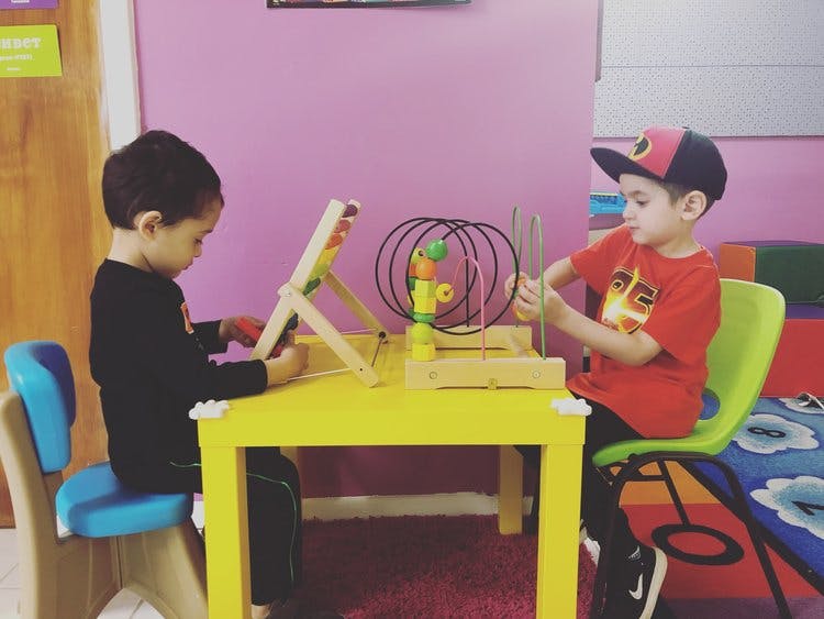 Two children playing with educational toys at a yellow table