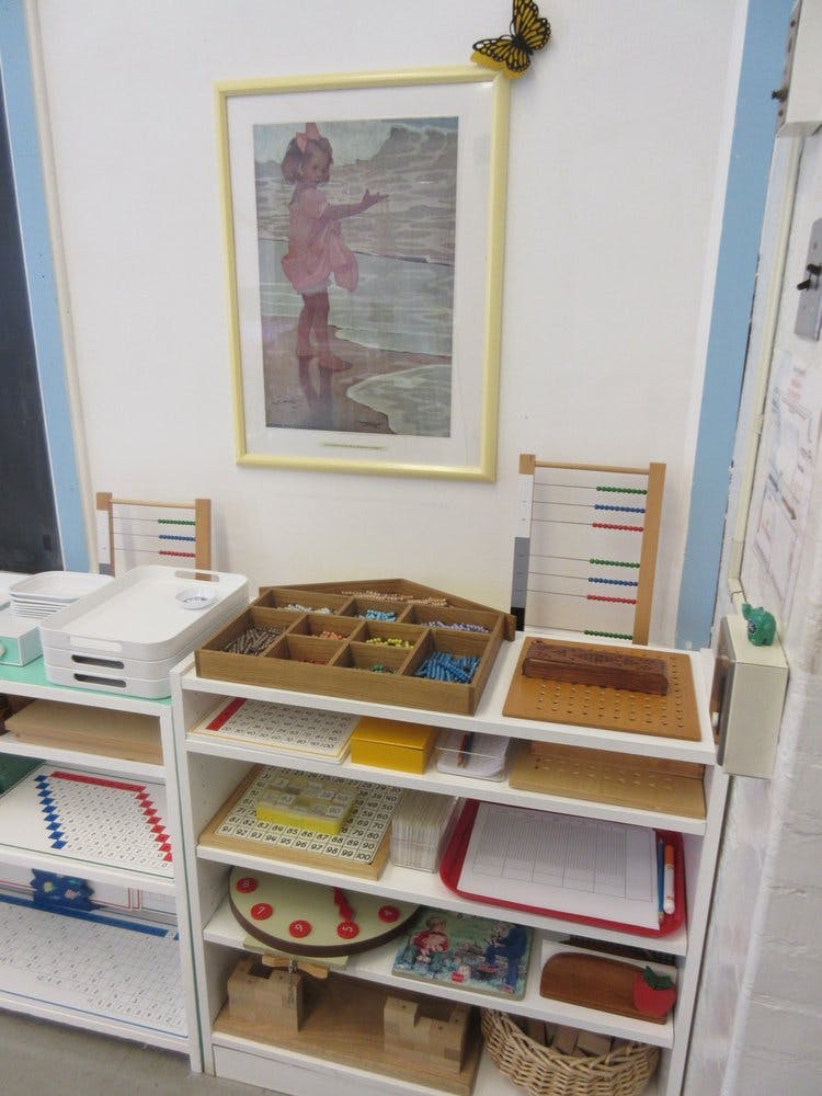 Shelves with various educational materials and a framed picture on the wall