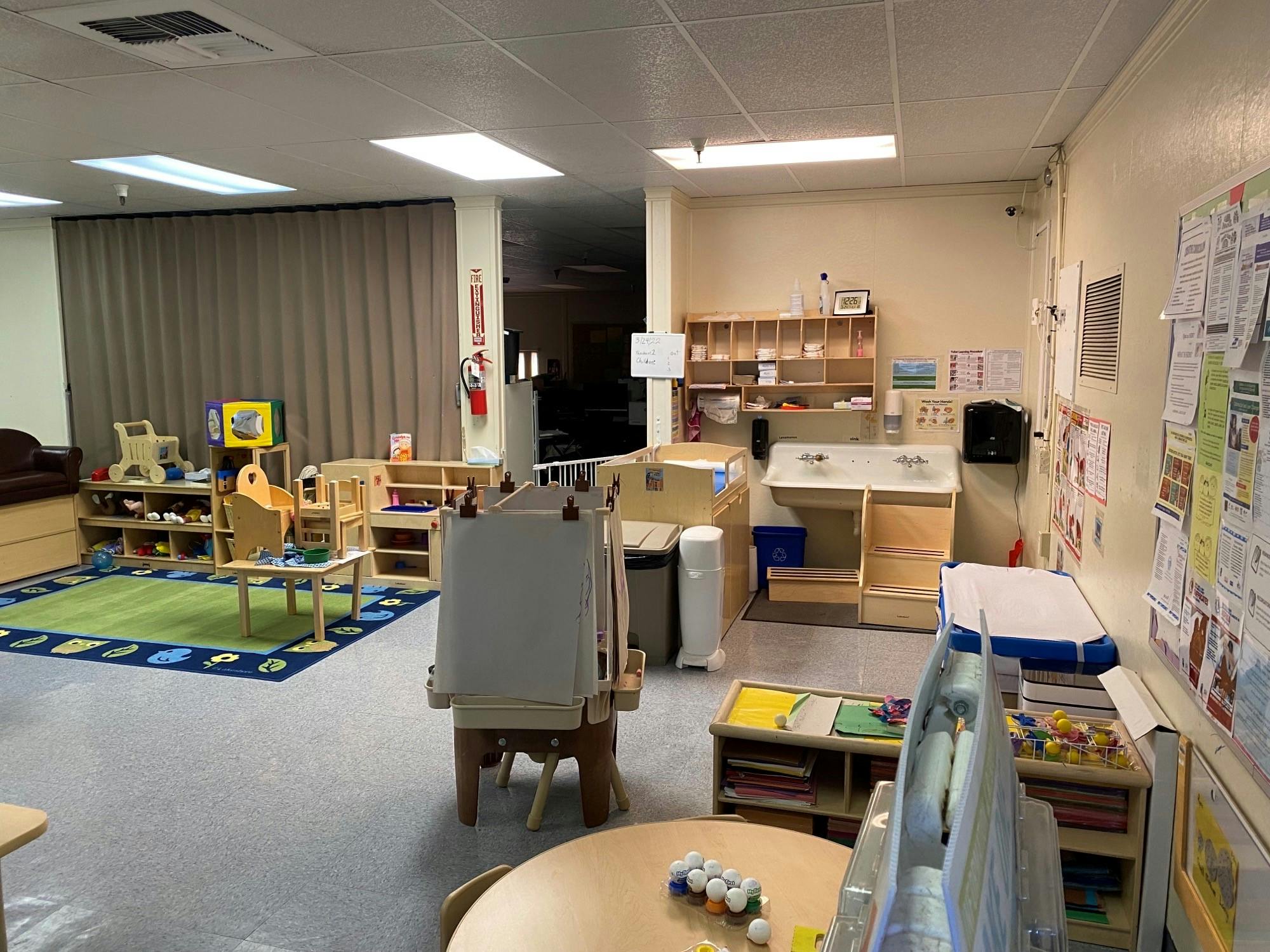 Empty classroom with small tables, chairs, and an easel