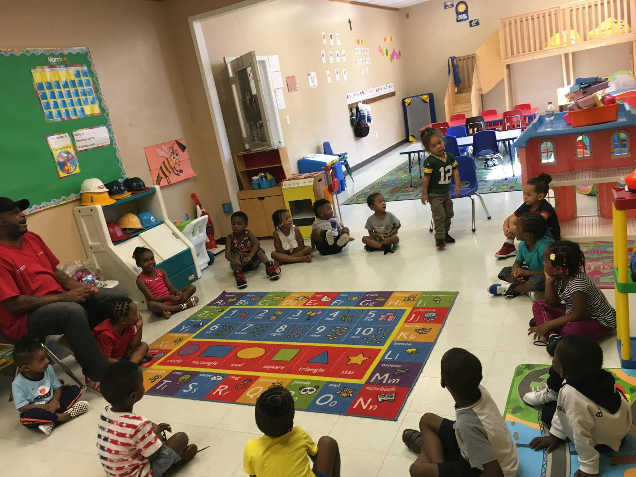 Adult and children sitting on the floor in a classroom