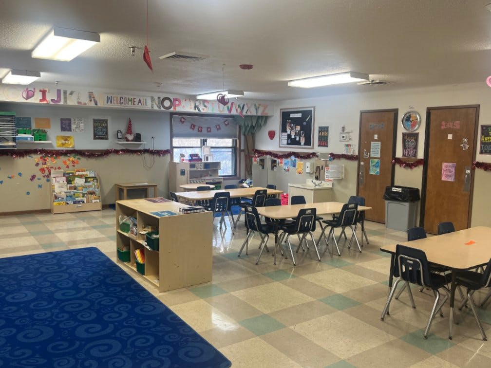 Empty classroom with tables, chairs, and learning materials