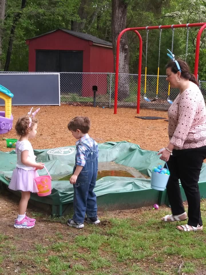 Adult and two children with baskets on a playground
