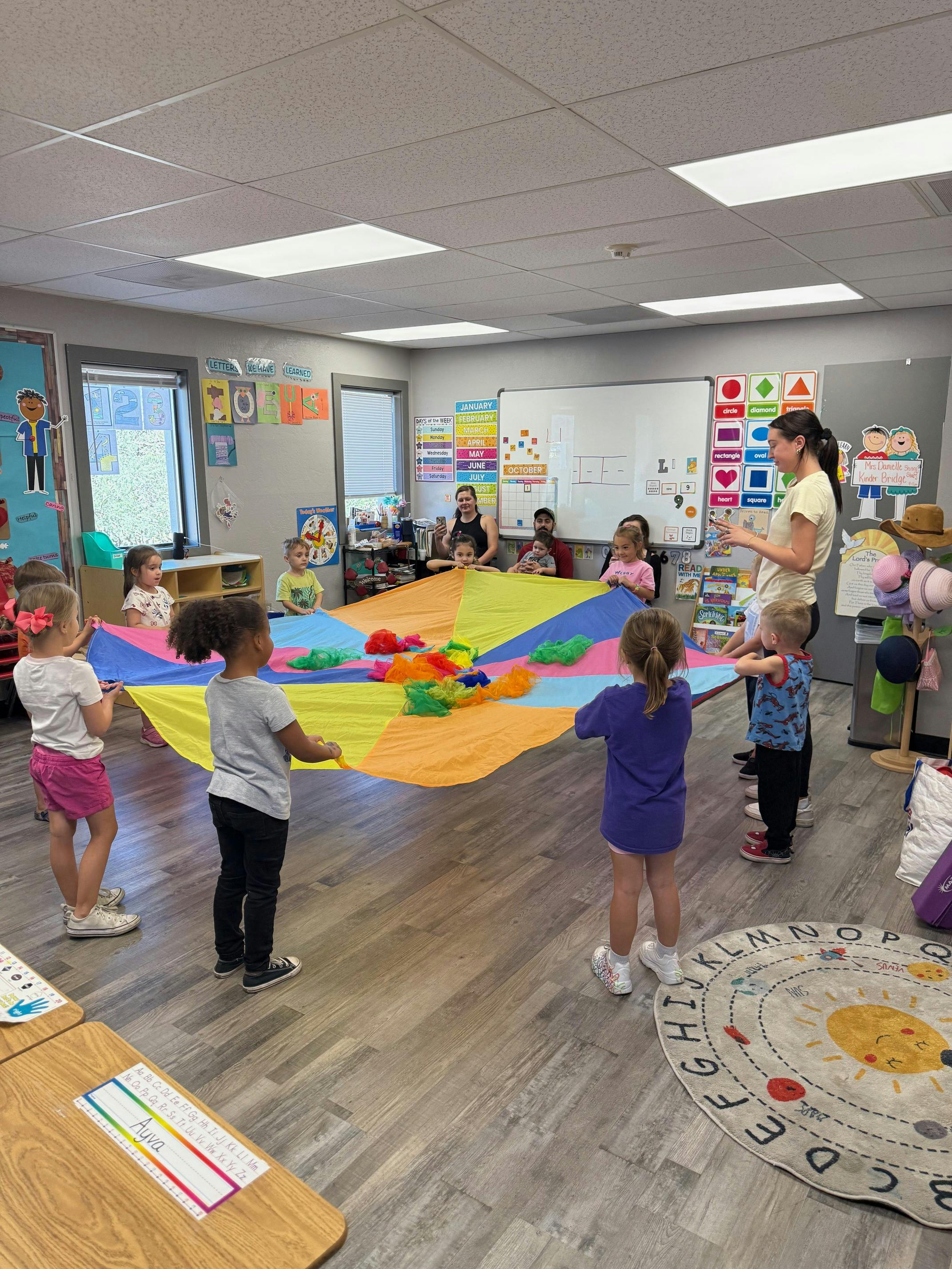 Children holding a colorful play parachute in a classroom